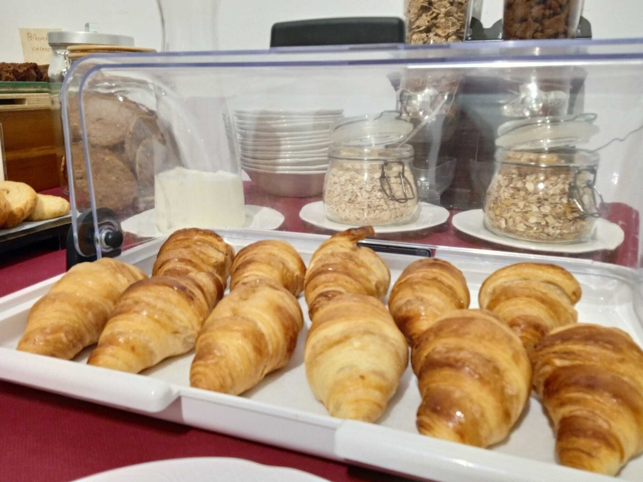 A display case with croissants and various food items.