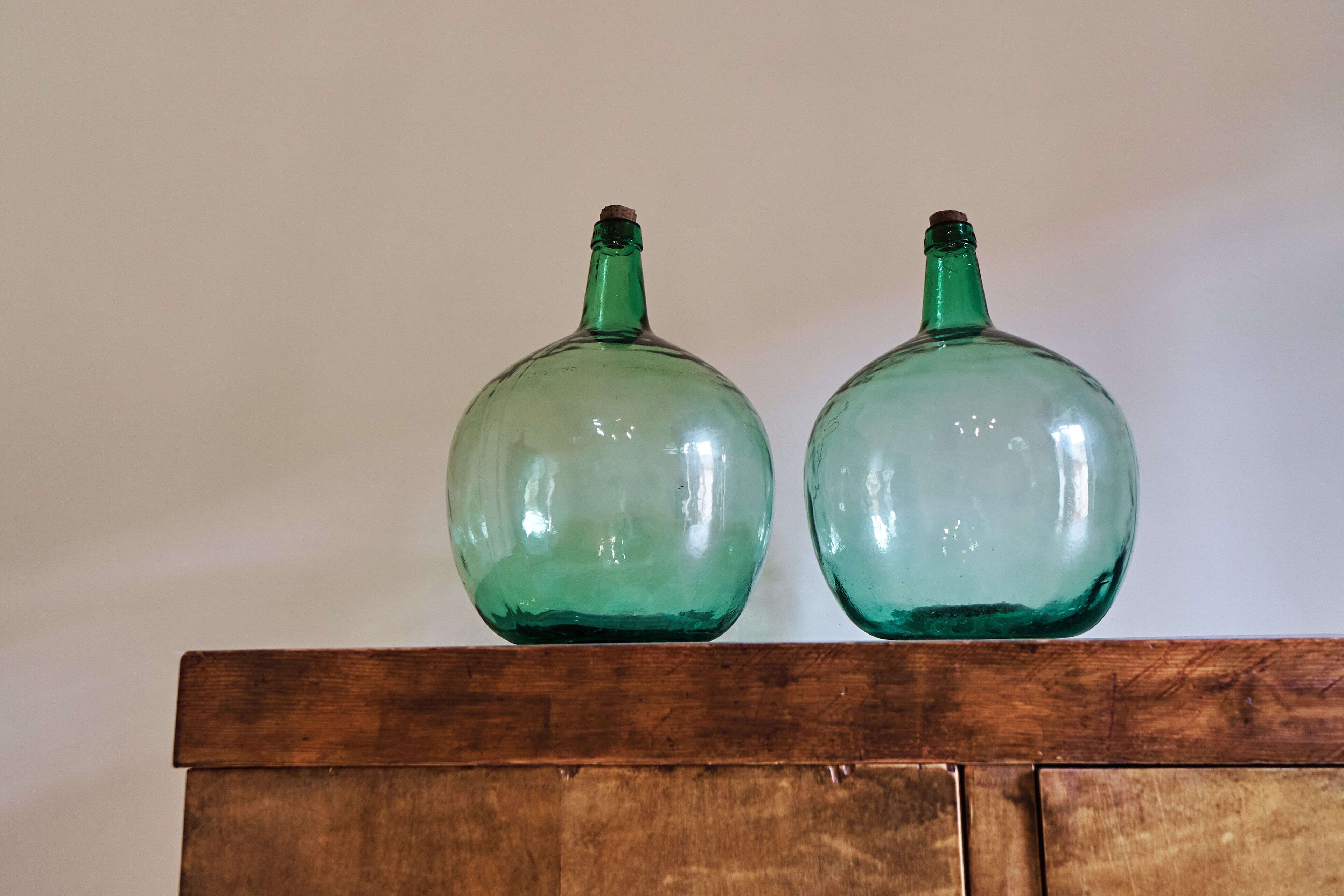 Dos botellas de vidrio verde sobre un estante de madera.