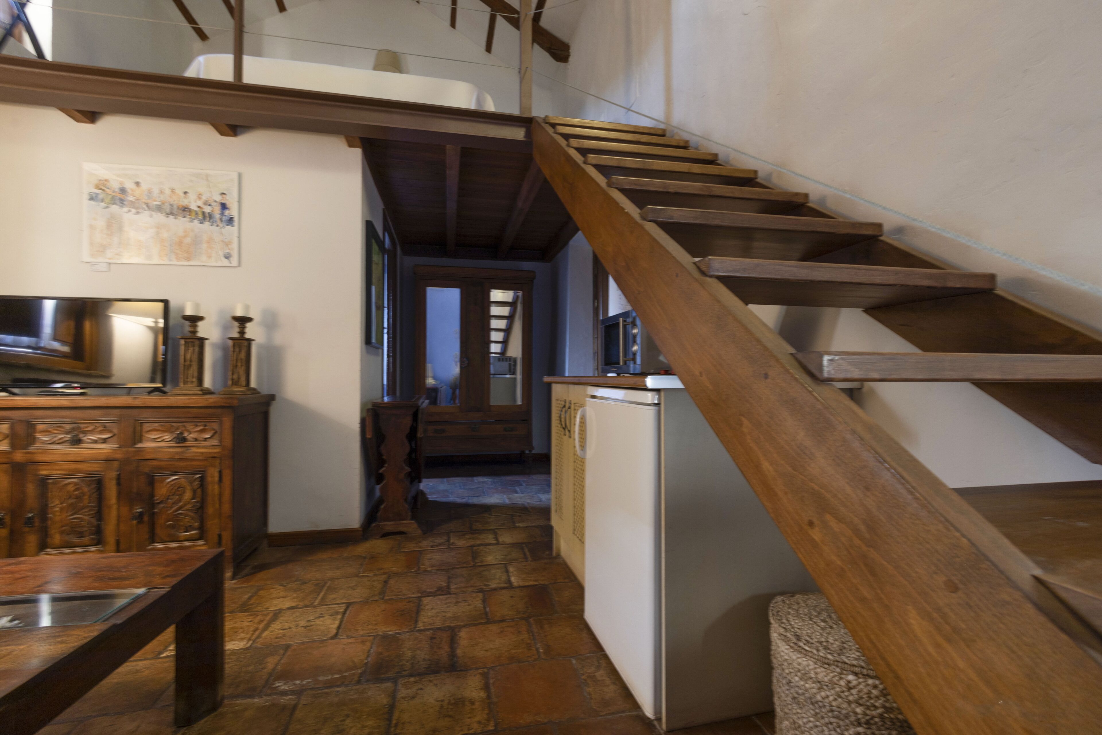 Una cocina con escalera de madera, un refrigerador y una mesa de comedor.