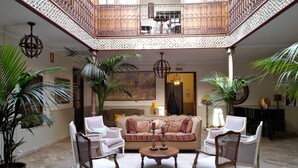 A spacious atrium with a high ceiling, a central seating area with a sofa and chairs, and a staircase with ornate railings. - La Vida de Antes (Consuegra)