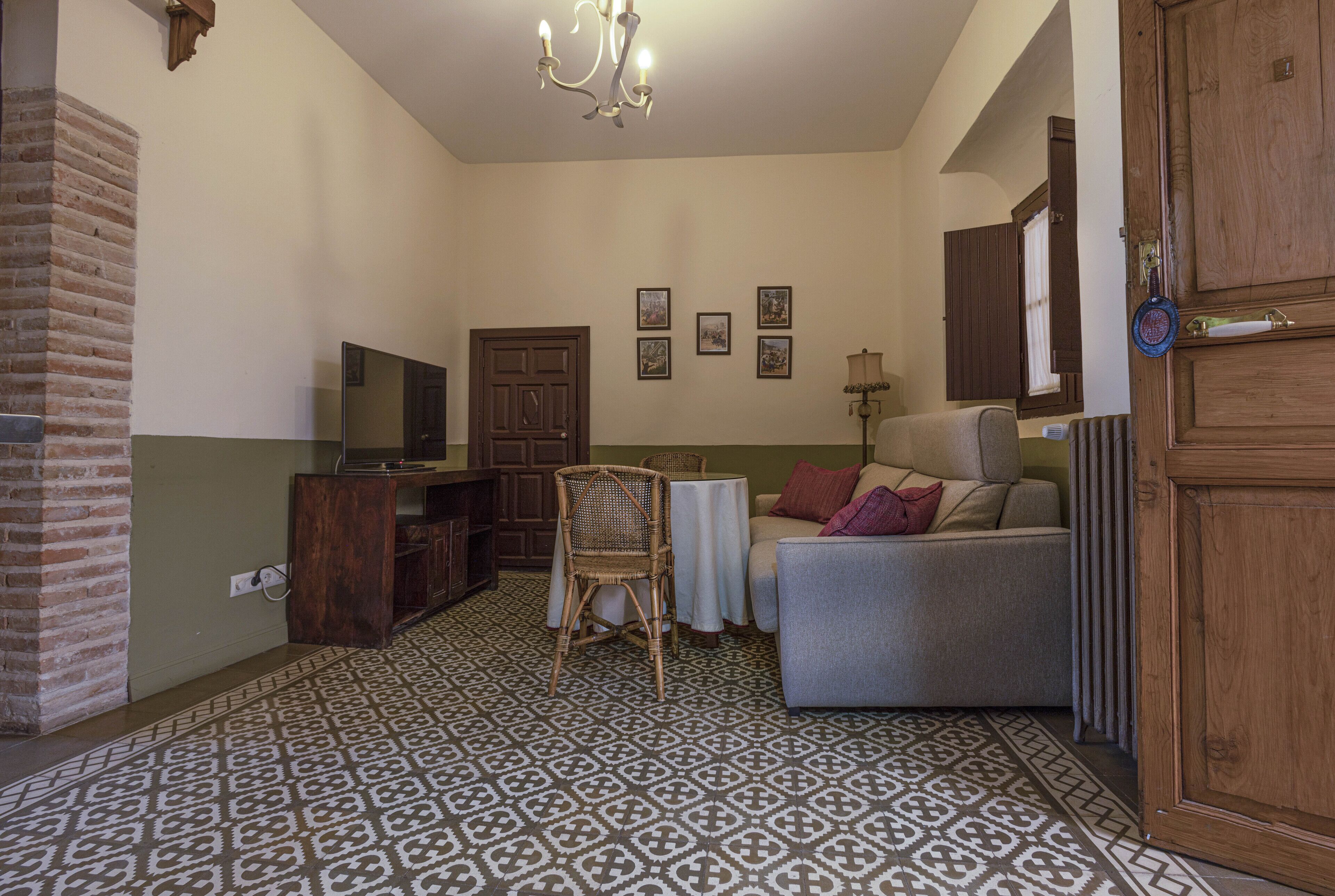 Una sala de estar con suelo estampado, un televisor, un sofá, una silla y una mesa.