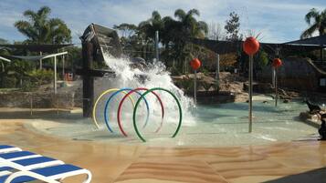 A water play area with a splash feature, a pool, and lounge chairs.