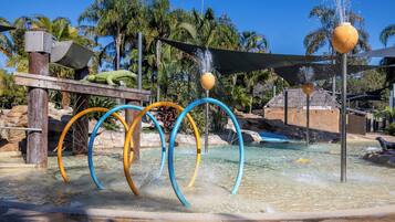 Un parco acquatico con piscina, scivoli d'acqua e un edificio con tetto di paglia.