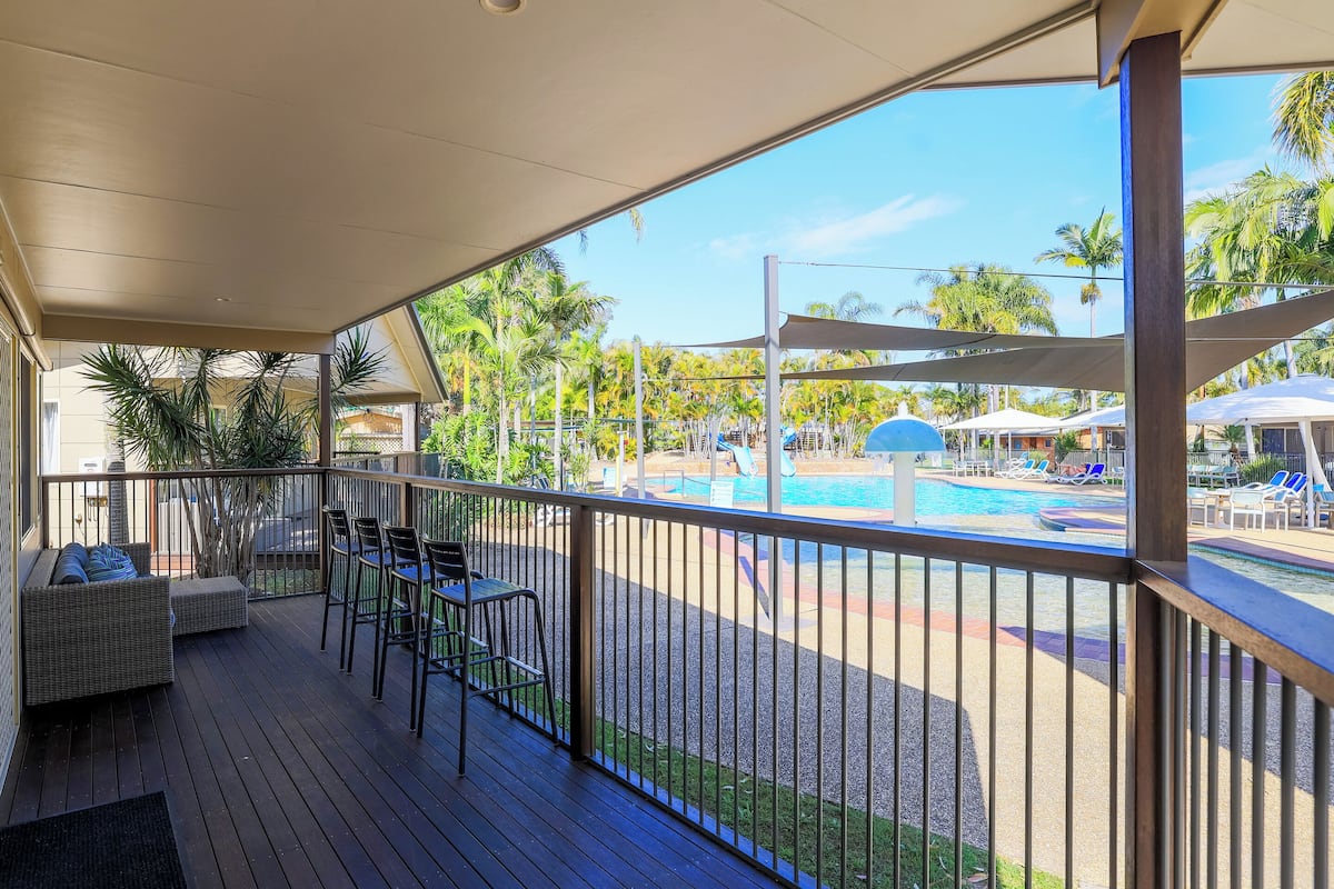 A covered outdoor area with a pool, lounge chairs, and a seating area with a sofa and chairs.