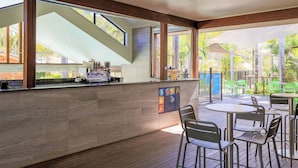 A modern bar area with a counter, seating, and a view of the outdoors. - NRMA Blue Dolphin Yamba Holiday Resort (Yamba)