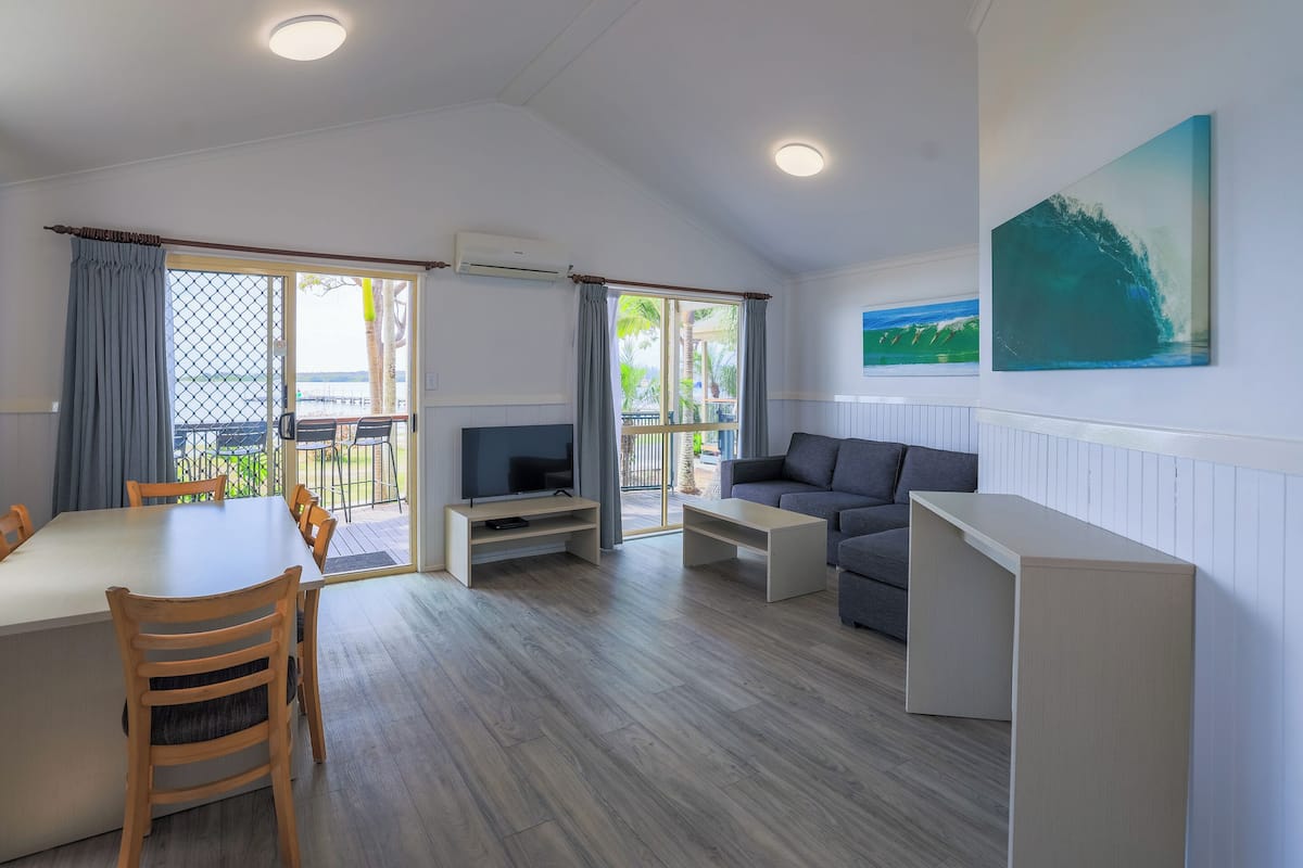 A spacious living area with a dining table, sofa, and TV.