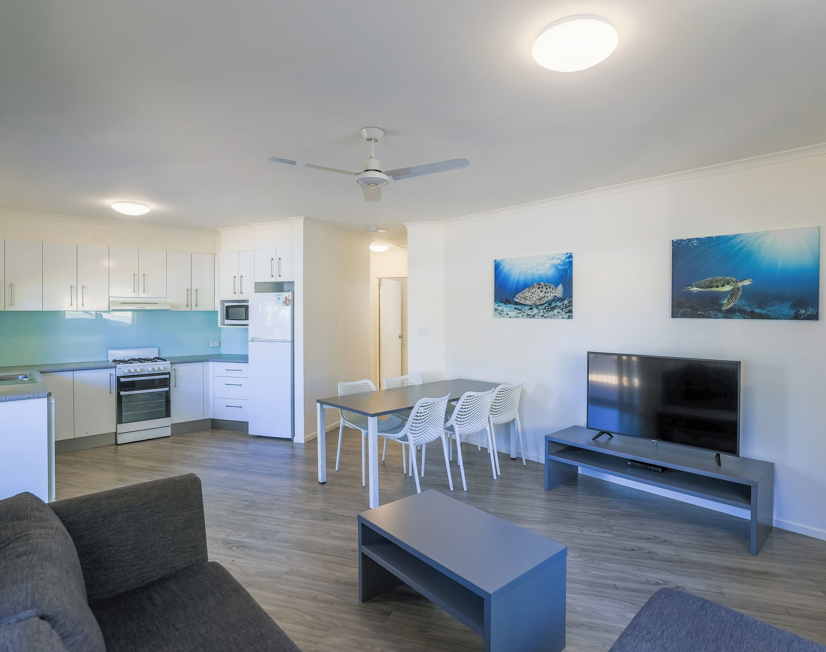 A modern apartment with a kitchen, dining area, living room, and a TV.