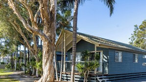 A single-story house with a porch, surrounded by trees and a clear sky. - NRMA Blue Dolphin Yamba Holiday Resort (Yamba)