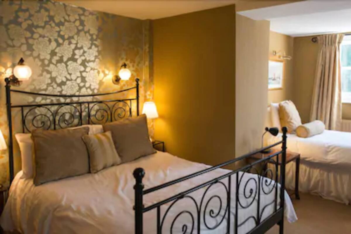 A hotel room with a large bed, a smaller bed, and a window with curtains.