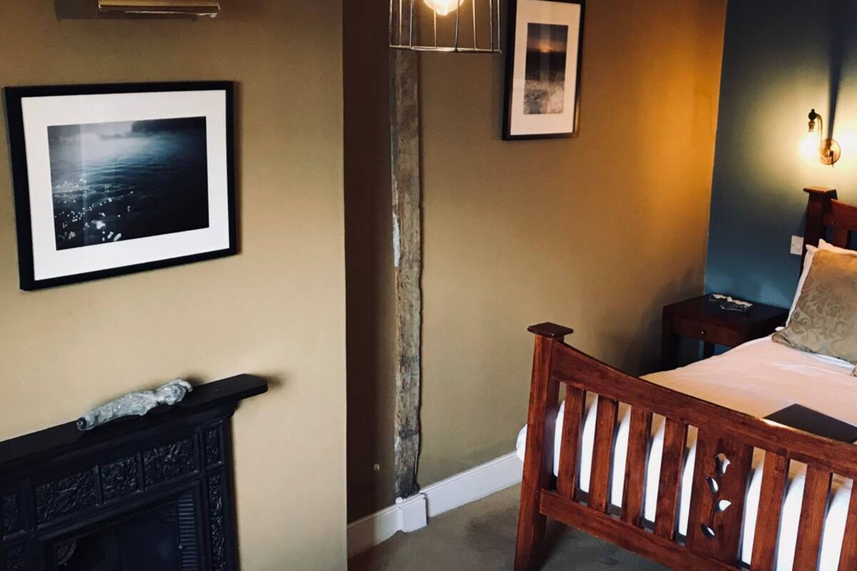 A bedroom with a wooden bed, a fireplace, and framed pictures on the walls.