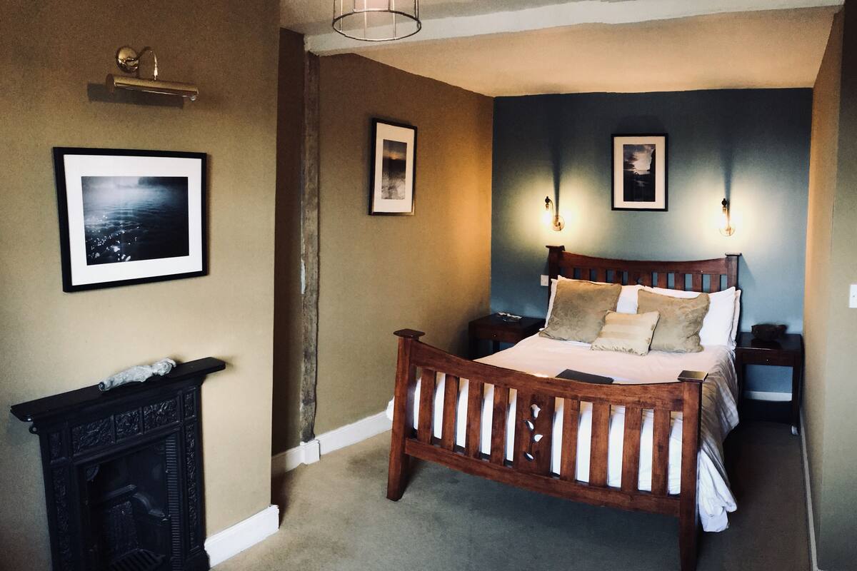 A bedroom with a wooden bed, a fireplace, and two wall-mounted lights.