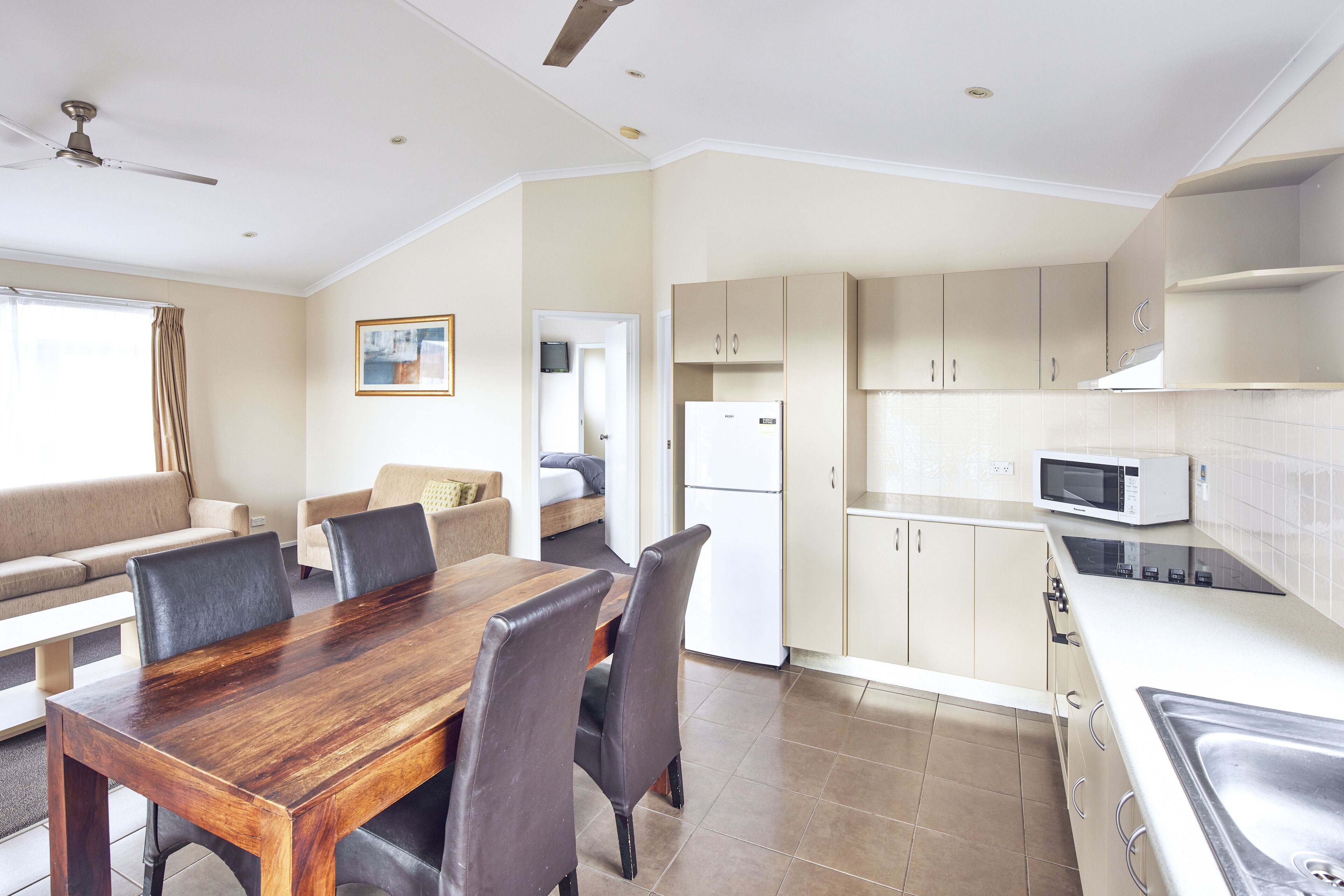A modern kitchen with a dining area, a refrigerator, a microwave, and a ceiling fan.