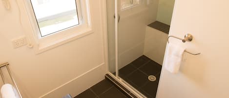 A bathroom with a white sink, a glass shower enclosure, and a window providing natural light.