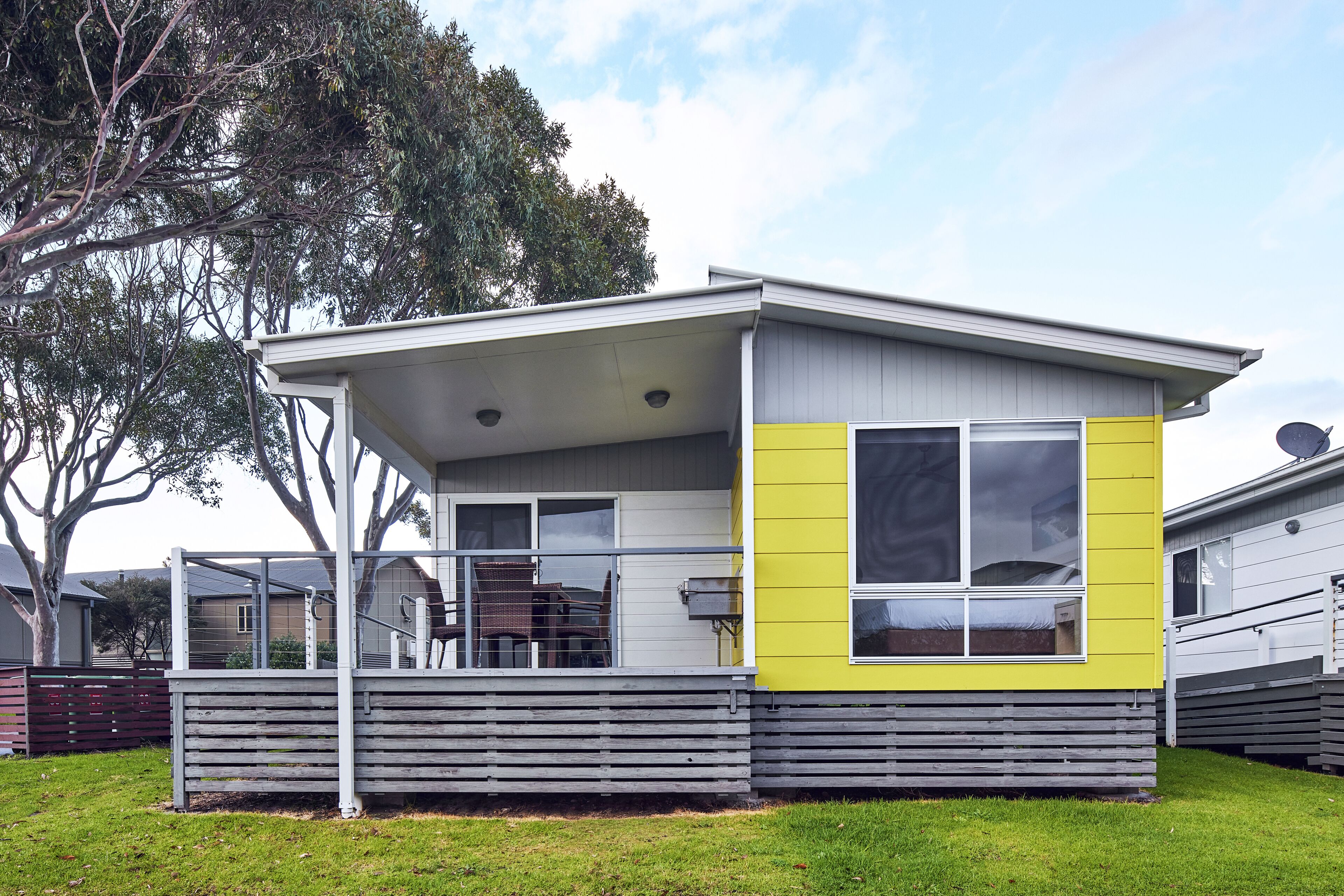 A modern single-story house with a flat roof, large windows, and a covered porch area.