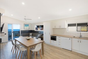 Una cocina moderna con comedor, armarios blancos y vistas al exterior.