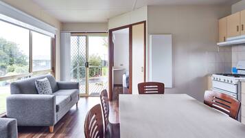 Una cocina moderna con comedor, sofá y vistas por un ventanal corredero.