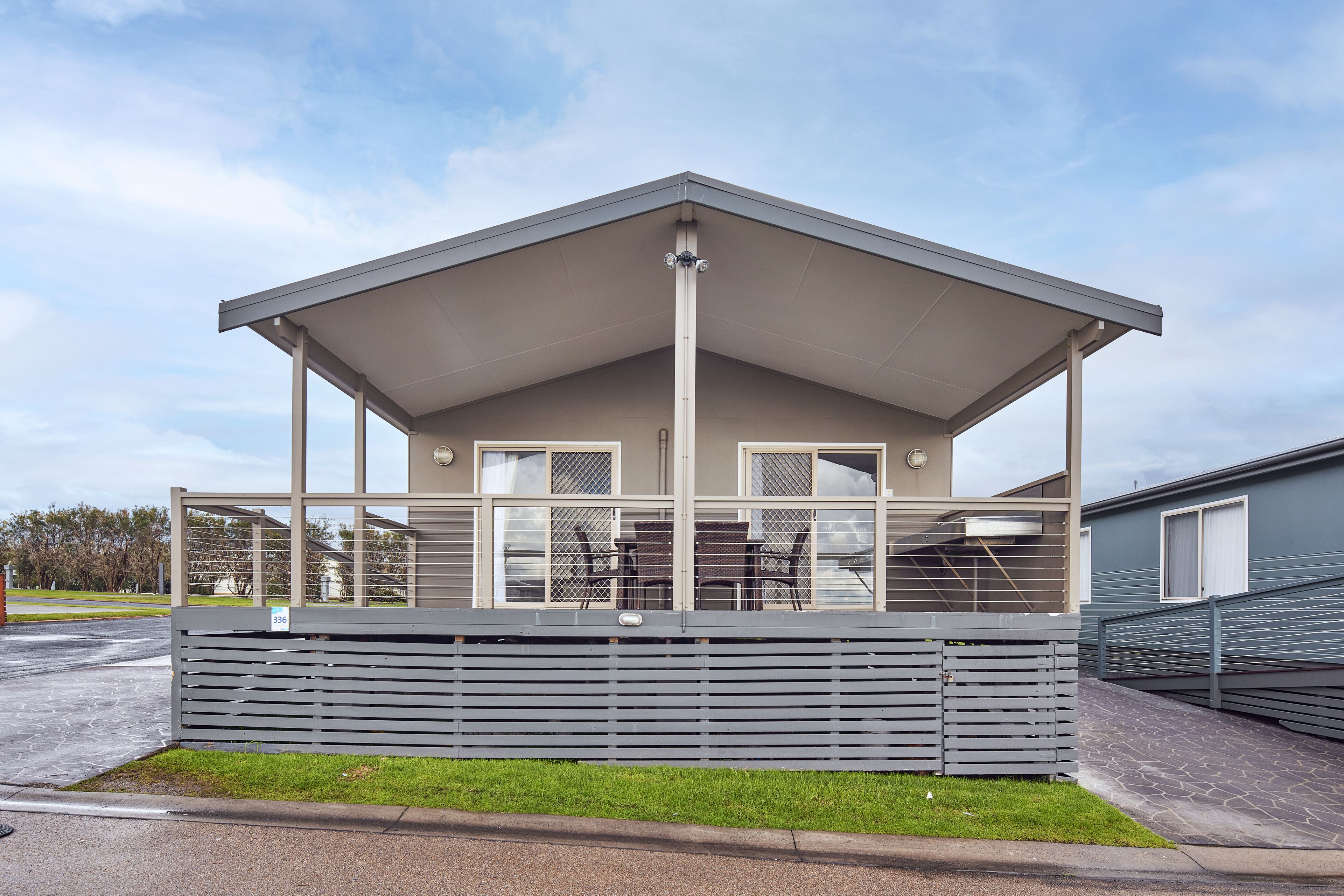 A modern building with a covered patio area, large windows, and a fenced outdoor seating area.