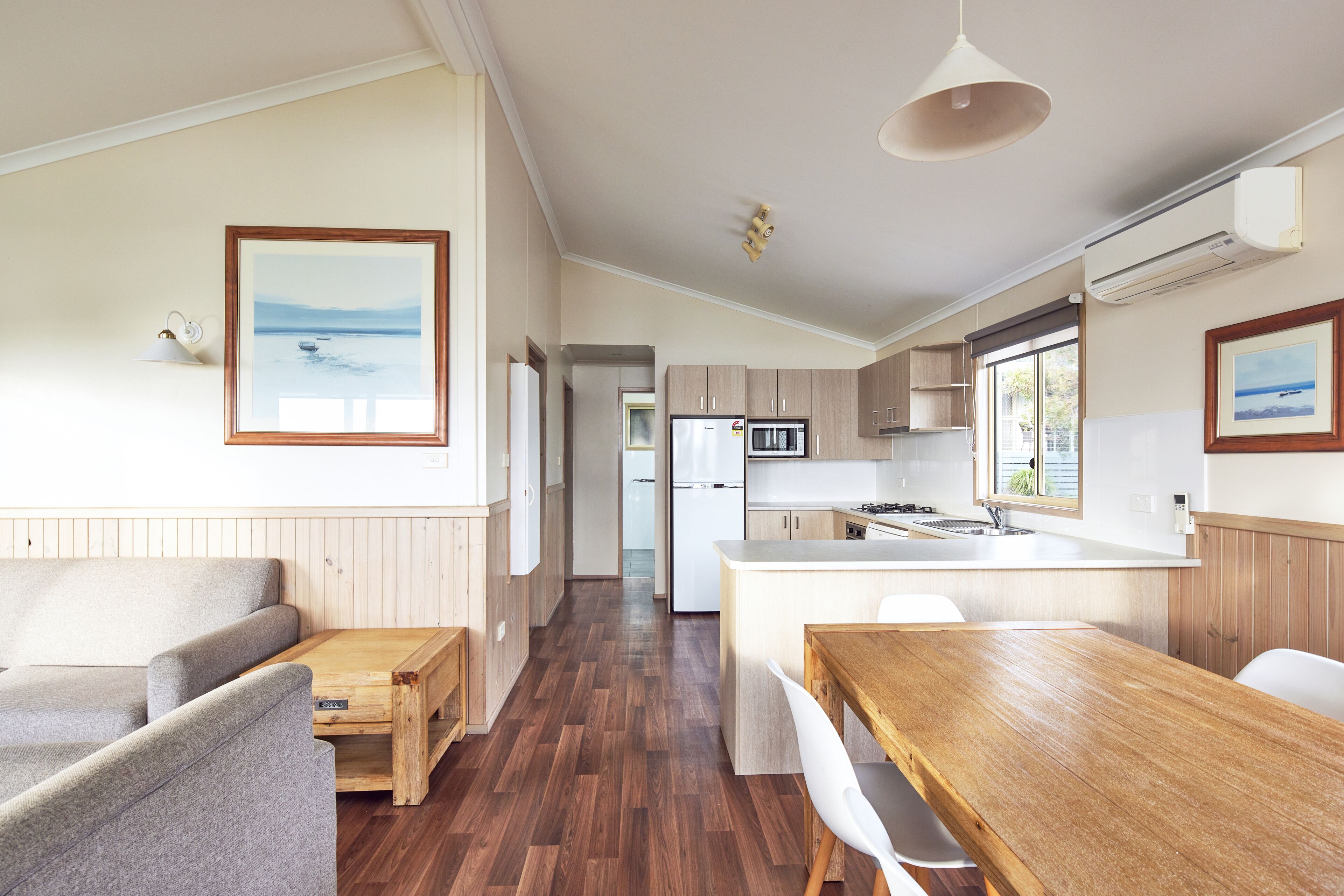 A modern kitchen with wooden cabinets, a central island, and a dining area with a wooden table and chairs.