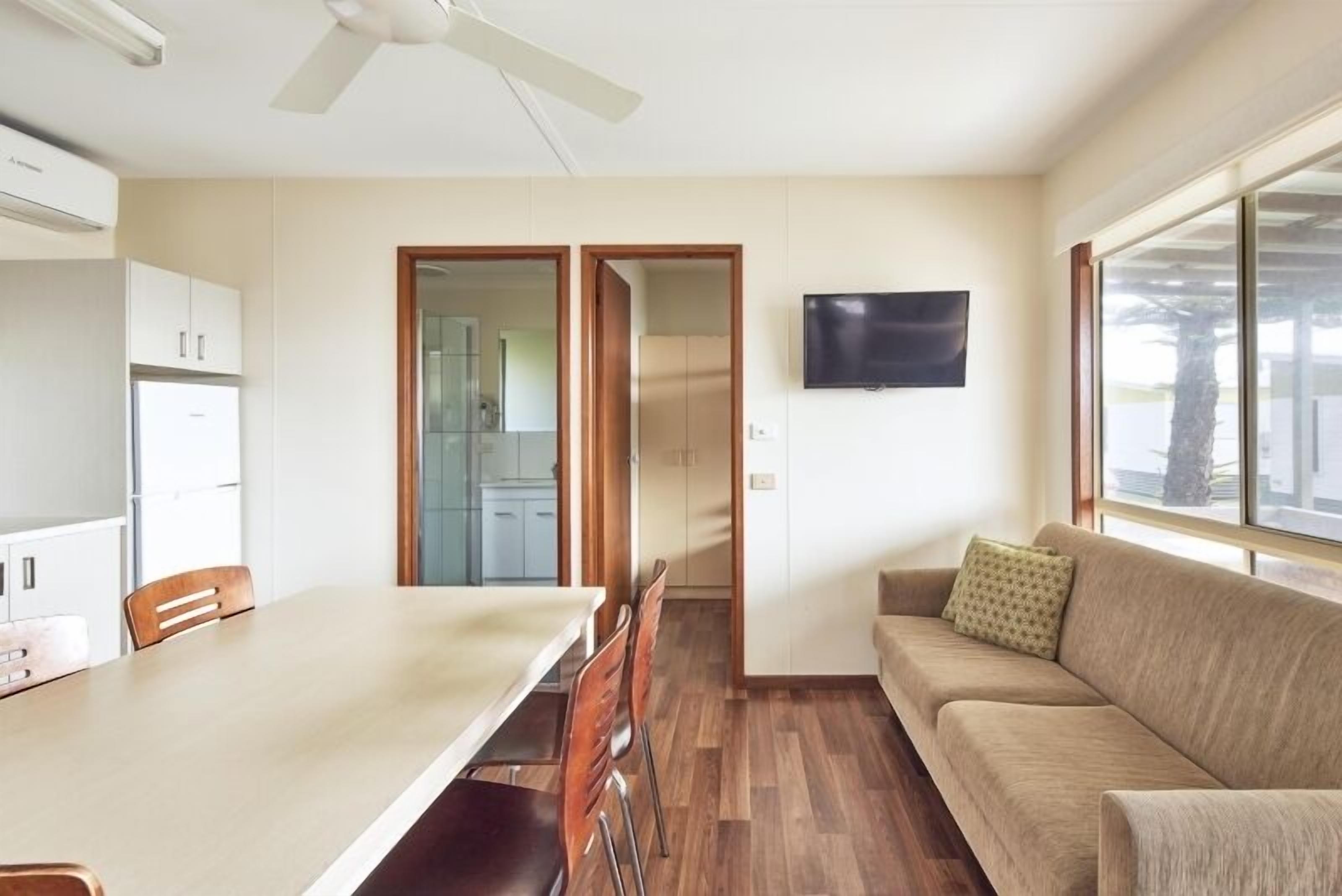 A modern kitchen with white cabinets, a dining table with chairs, and a large window.