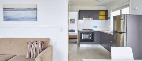 A modern kitchen with grey cabinets, a stainless steel refrigerator, and a microwave.