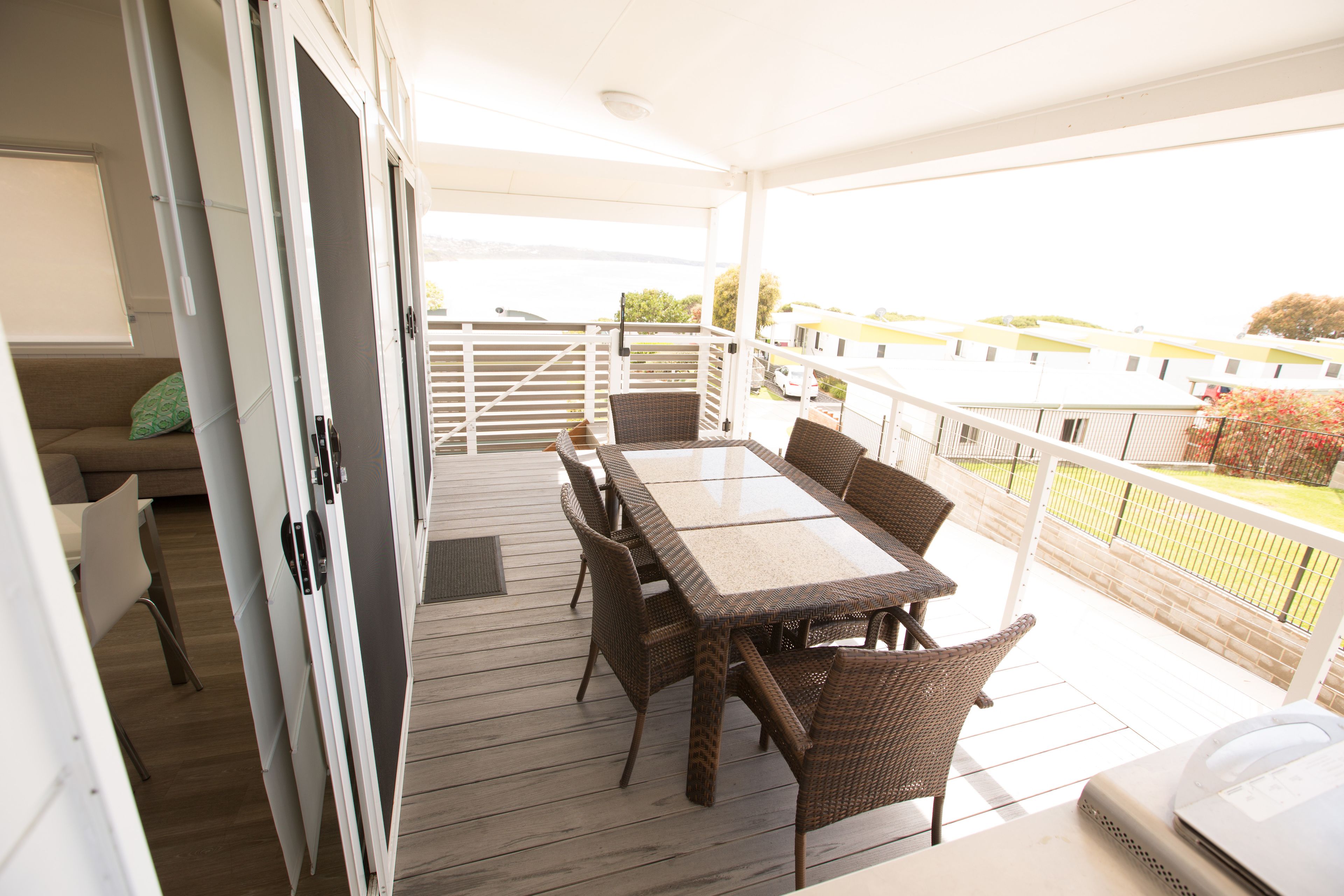 Une terrasse extérieure couverte, avec une table et des chaises pour les repas, un canapé et un ordinateur portable posé sur une table.