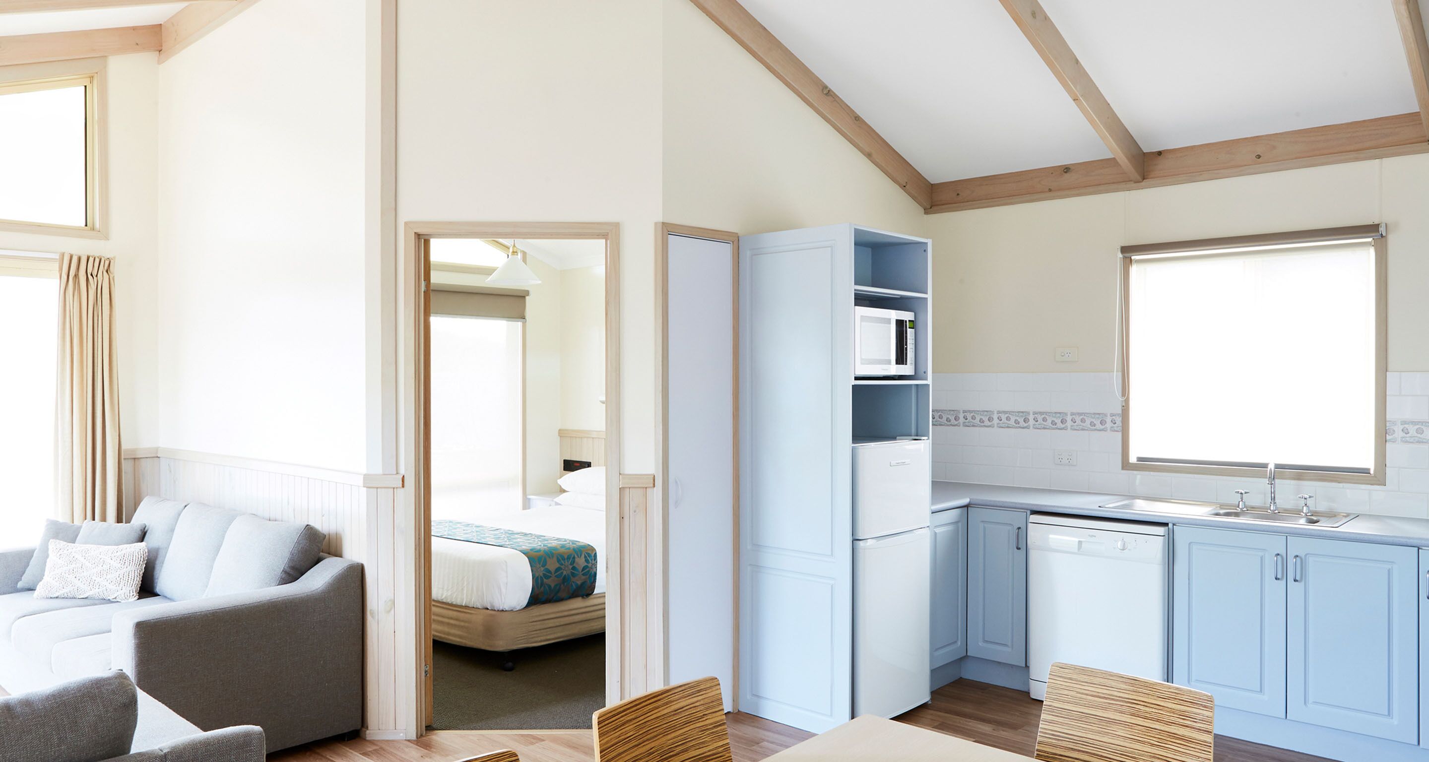 Een kleine kamer met een bed, een kitchenette en een zithoek.