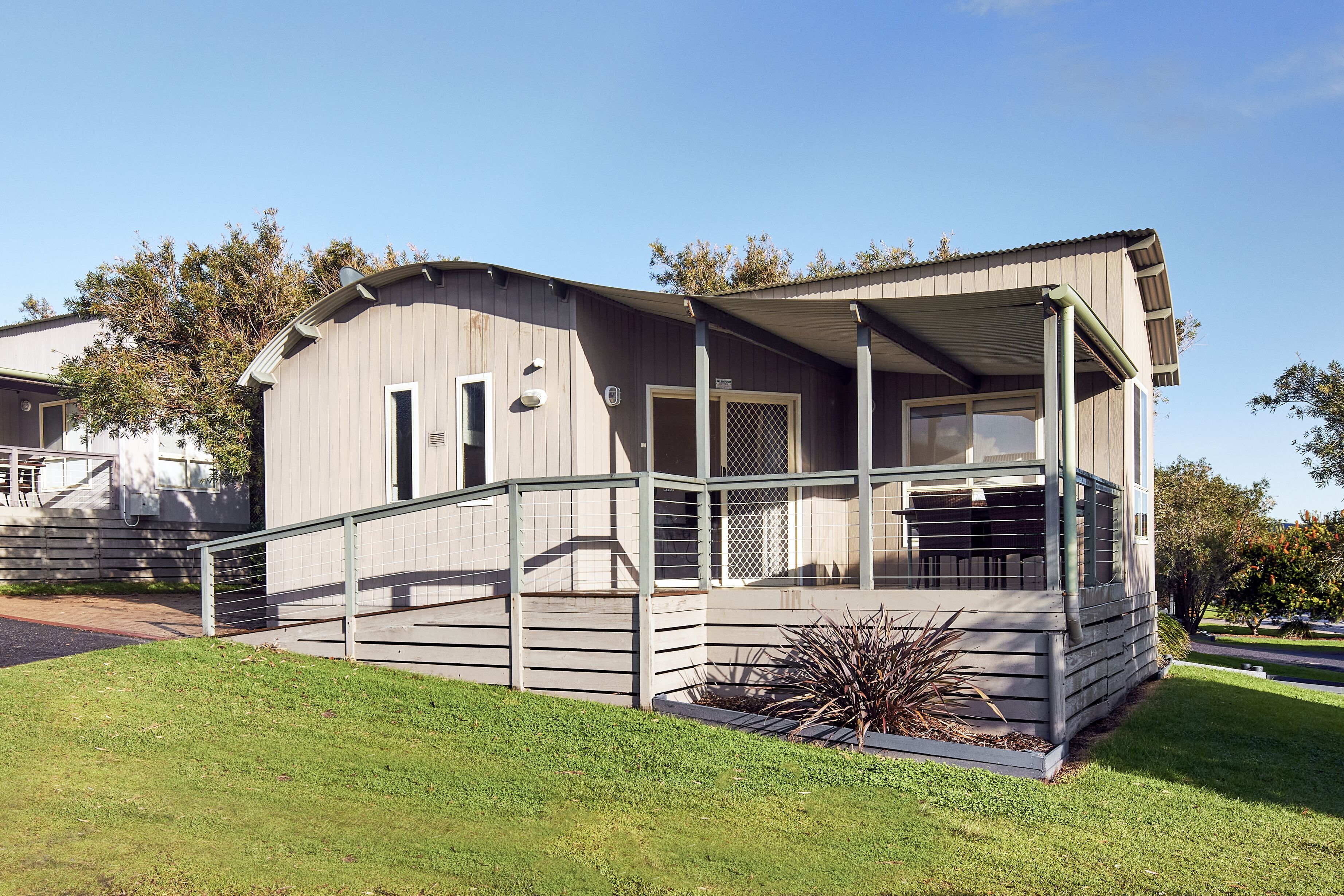A single-story mobile home with a covered porch and a small garden area.