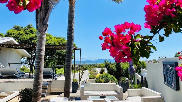 A rooftop terrace with lounge chairs, a pergola, and a view of the sea and mountains. - Southern Cross Guest House (Cape Town)