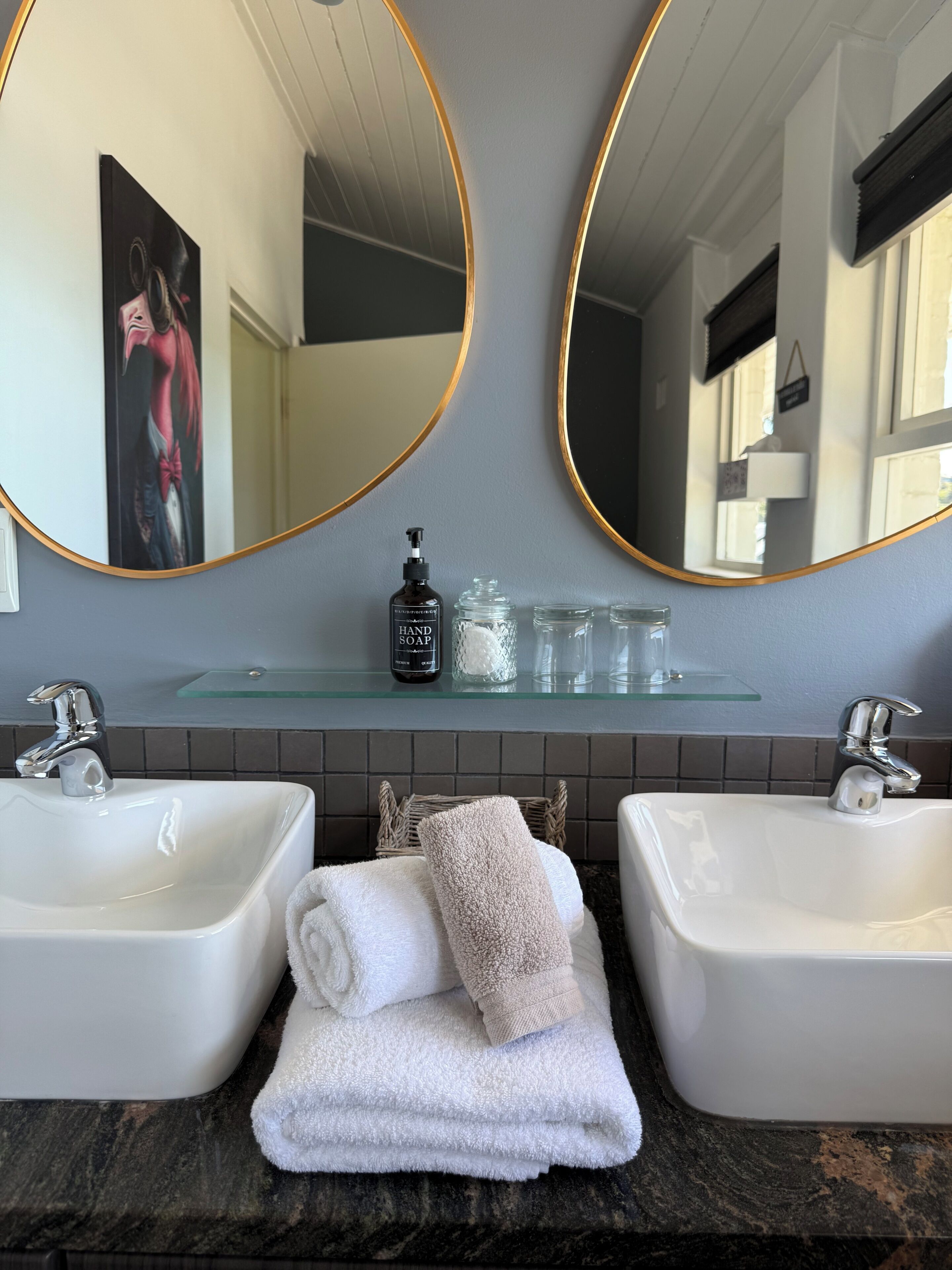 A bathroom with two sinks, a large mirror, and a towel rack.
