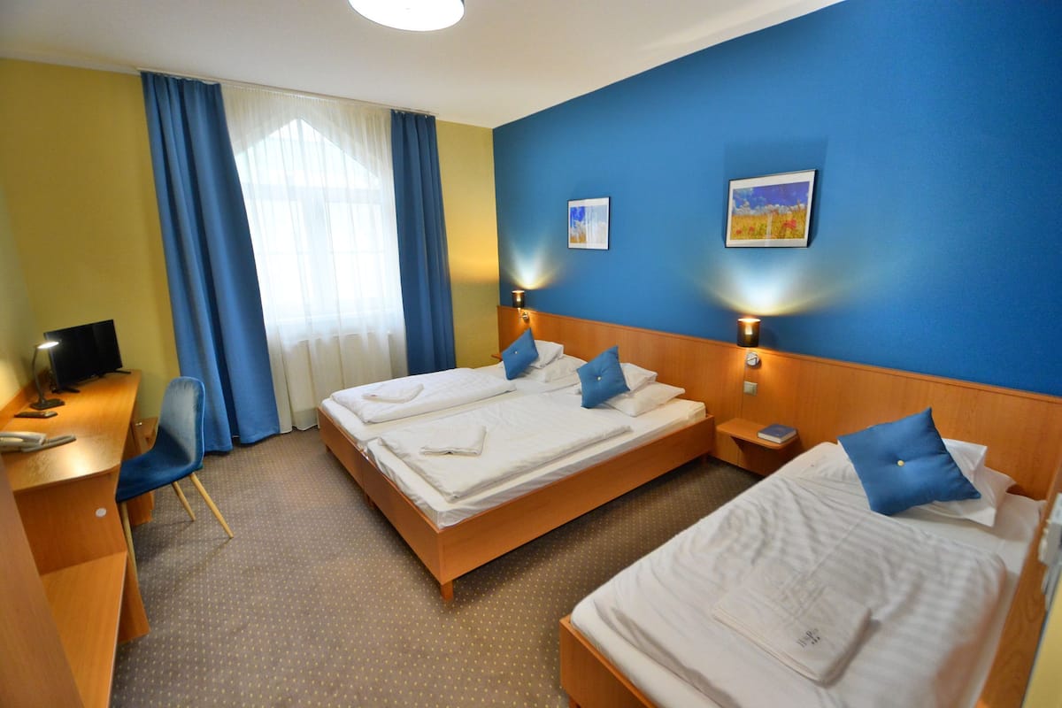 Une chambre d’hôtel avec deux lits, un bureau et une chaise.