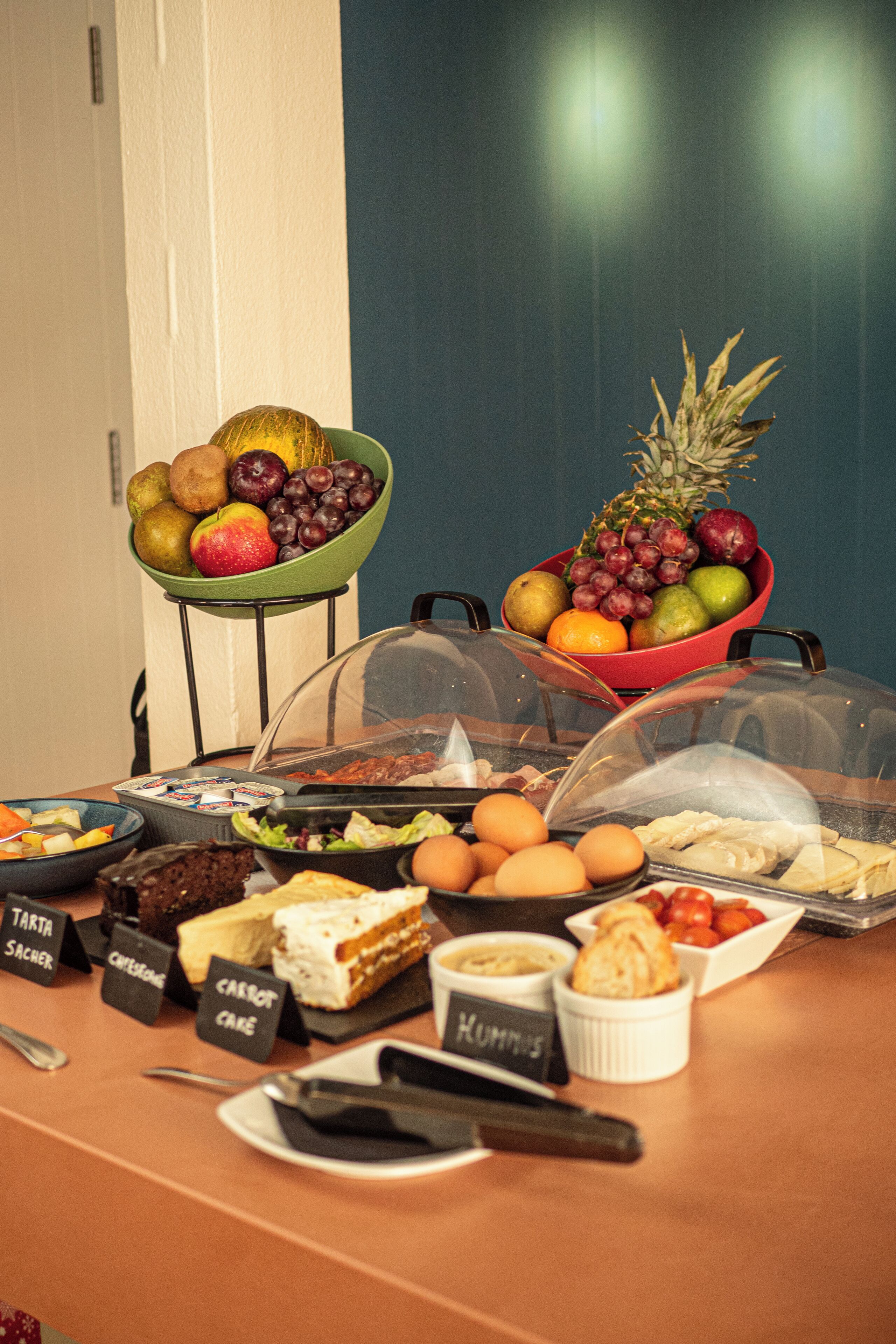 Una mesa de buffet con diversos alimentos y un bol de fruta.