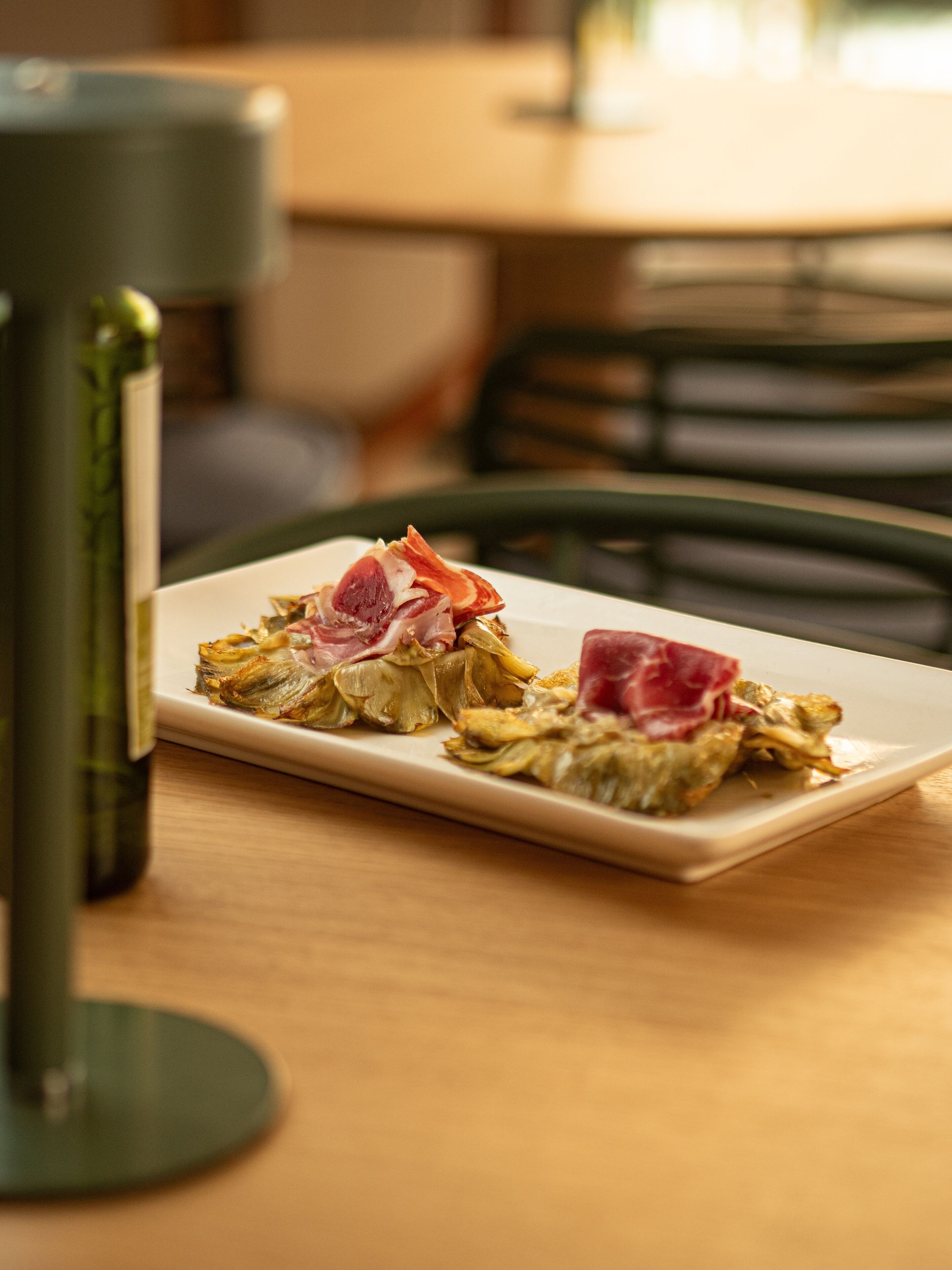 Un plato de comida con alcachofas y jamón serrano.