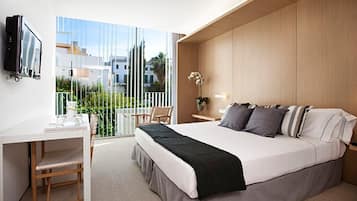 A modern bedroom with a large bed, a desk, and a TV.
