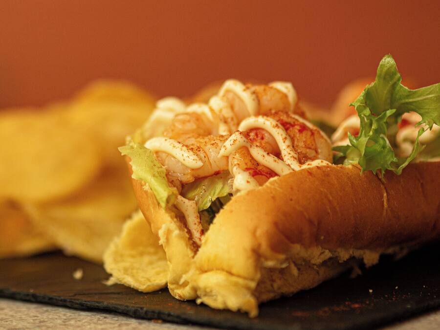 Un sándwich sobre un plato oscuro, con el fondo desenfocado.
