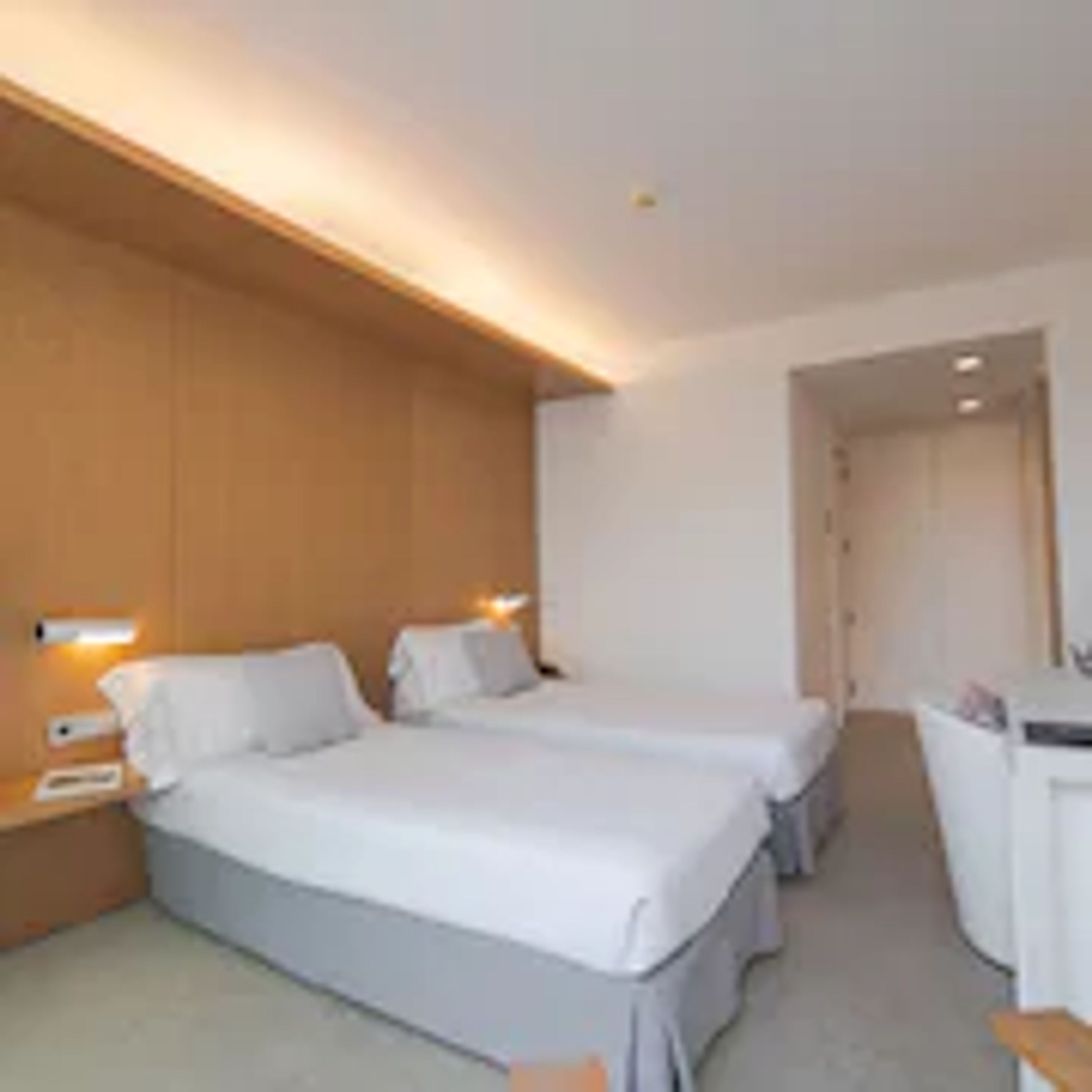 Ein Hotelzimmer mit zwei Betten, einem Schreibtisch und einem Stuhl.