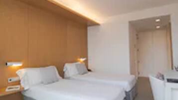 Ein Hotelzimmer mit zwei Betten, einem Schreibtisch und einem Stuhl.