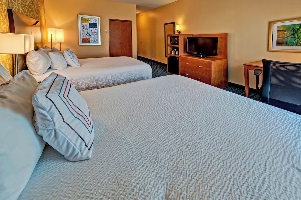 Une chambre d’hôtel avec deux lits, une télévision, un bureau et une chaise.