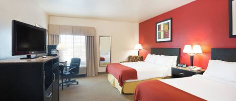 A hotel room with two beds, a desk with a TV, a chair, and a desk lamp.