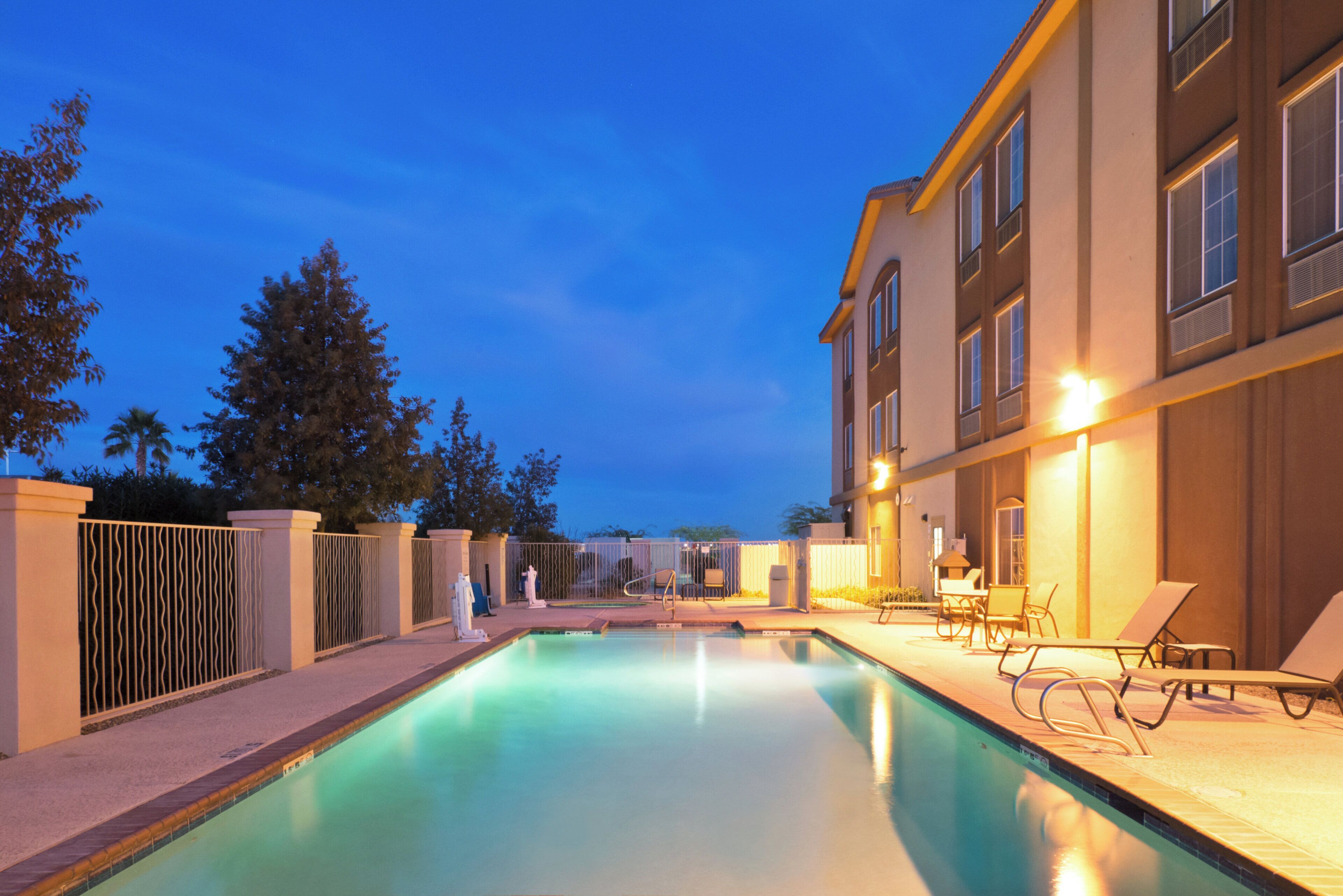 Una piscina al aire libre, sombrillas, sillones reclinables de piscina