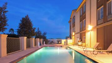 Una piscina al aire libre, sombrillas, sillones reclinables de piscina