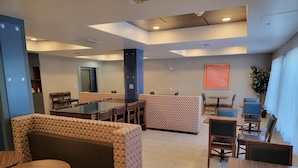 Un comedor moderno con cabinas, mesas y un revestimiento de pared con diseño.