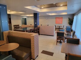 A modern dining area with booths, tables, and a patterned wall.