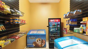 A grocery store with shelves stocked with snacks, a freezer with ice cream, and a refrigerator with beverages.