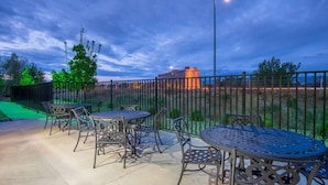 An outdoor patio with metal tables and chairs, a fence, and a building in the background. - Holiday Inn Express & Suites Casa Grande by IHG (Casa Grande)