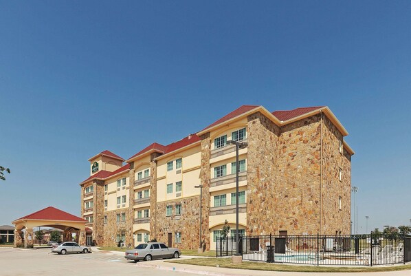 A multi-story hotel with a stone facade and red roofs. - La Quinta Inn & Suites by Wyndham McKinney (McKinney)