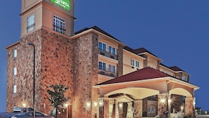 A hotel with a stone facade, a prominent sign, and a covered entrance. - La Quinta Inn & Suites by Wyndham McKinney (McKinney)