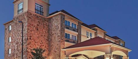 A hotel with a stone facade, a prominent sign, and a covered entrance.
