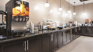 A self-service breakfast area with a fruit juice dispenser, hot water station, and various food options. - La Quinta Inn & Suites by Wyndham McKinney (McKinney)