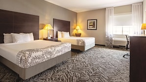 A hotel room with two beds, a desk, and a window with curtains. - La Quinta Inn & Suites by Wyndham McKinney (McKinney)
