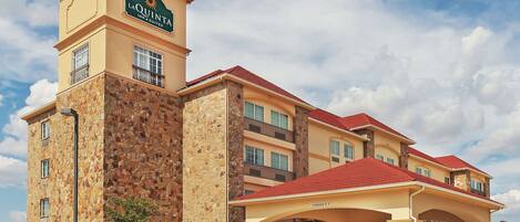 A hotel with a stone facade, multiple balconies, and a red roof.